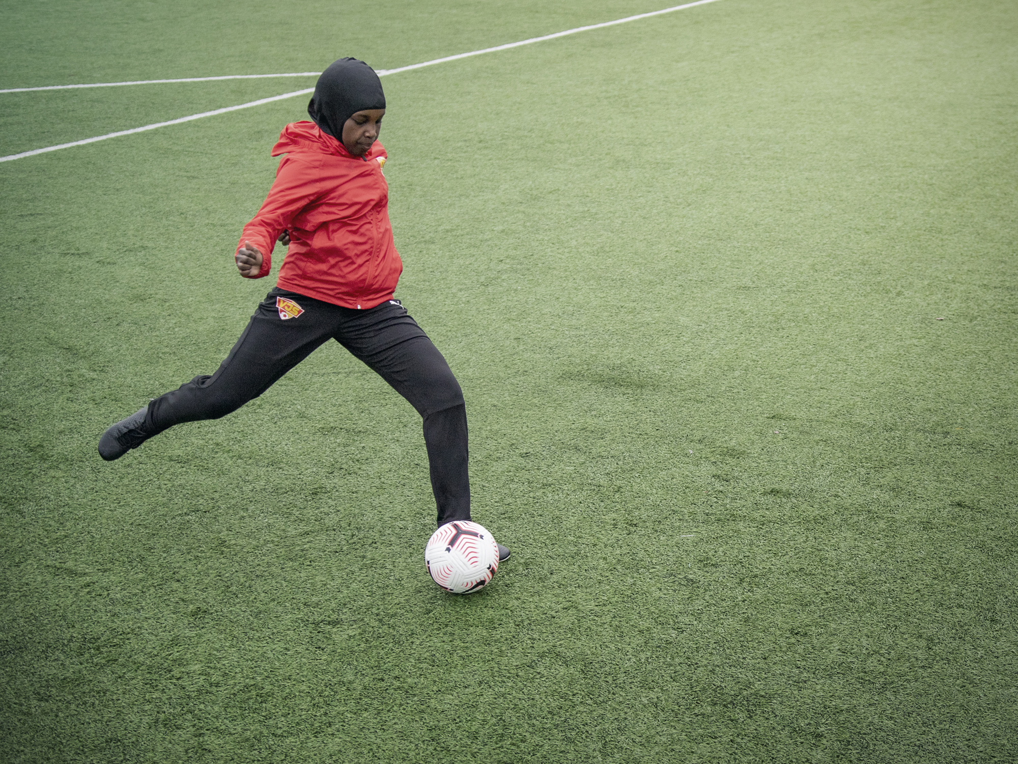 A hijabi player is playing the soccer.