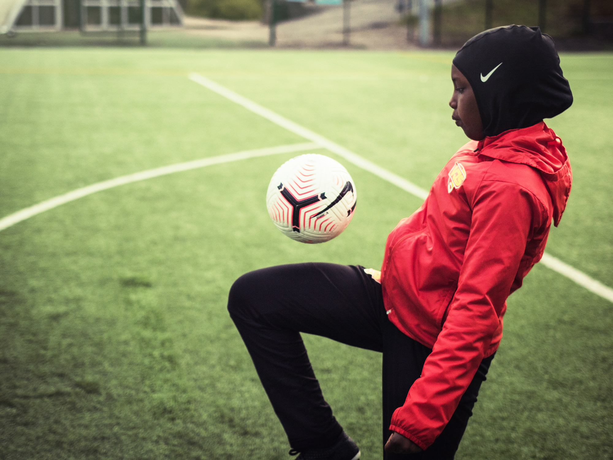A hijabi player is playing the soccer.