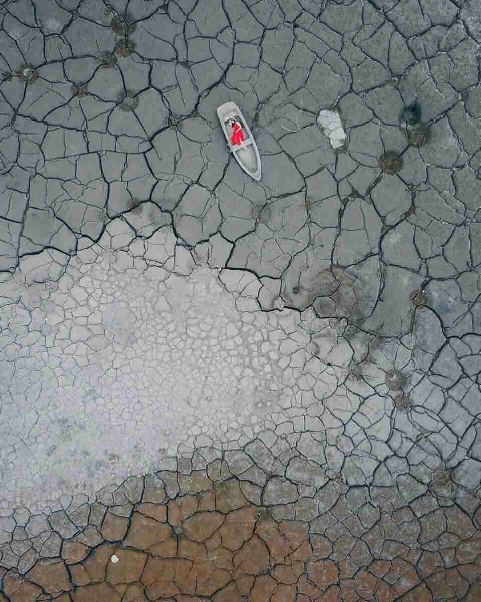A woman is lying on a boat in the lakebed.