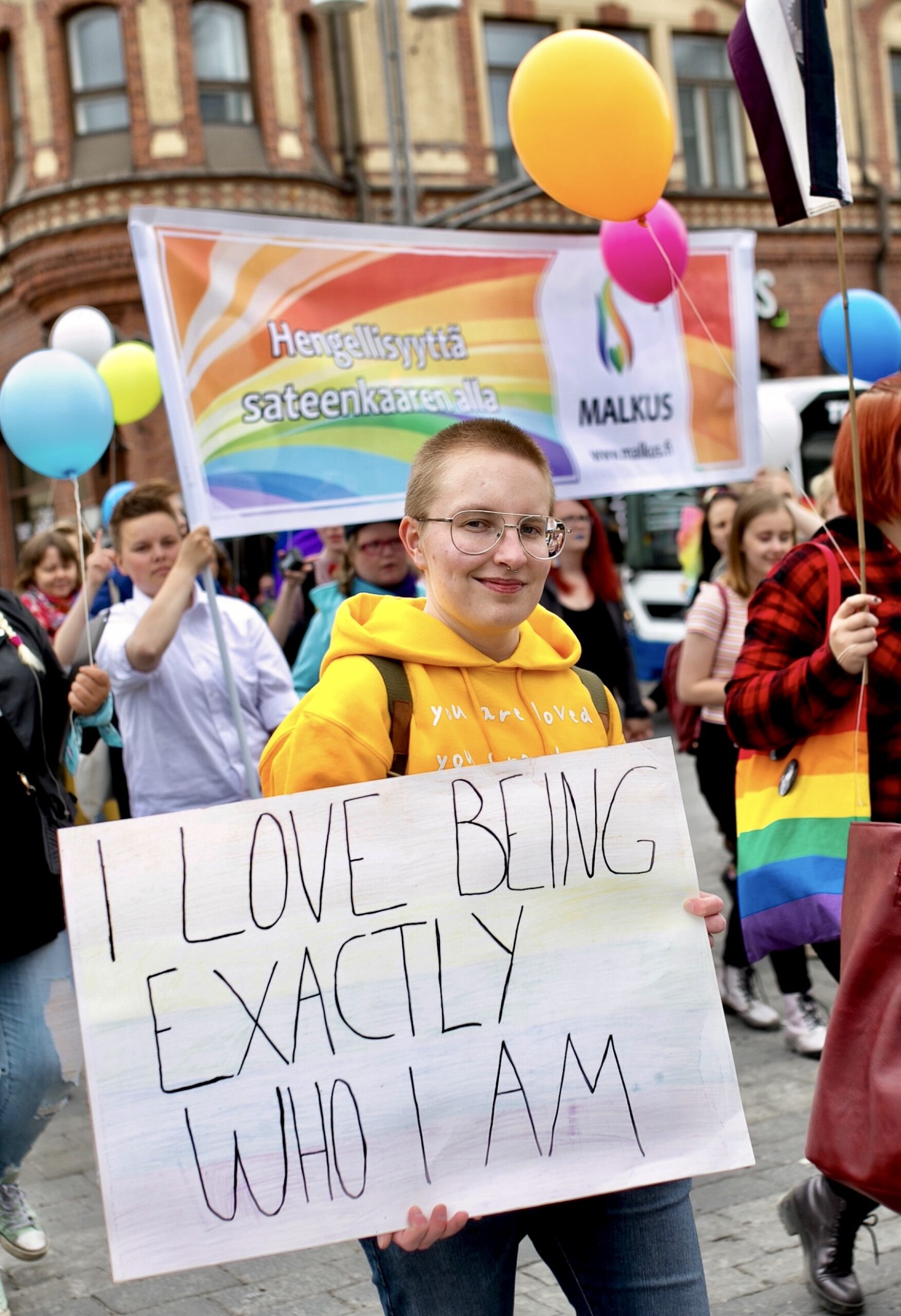 at a pride parade a person holding a sign saying i love being exactly who i am