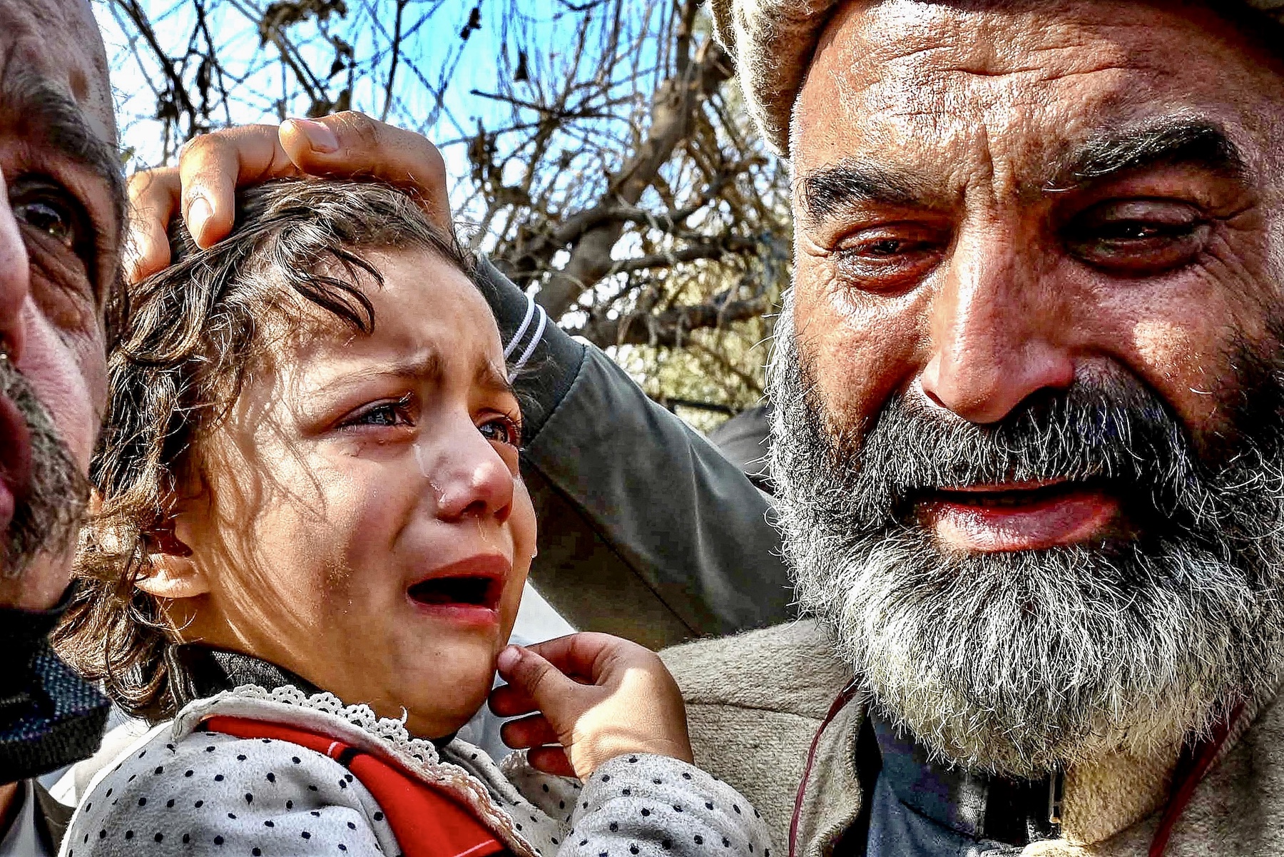 a pakistan man holding a baby girl and both of them are crying