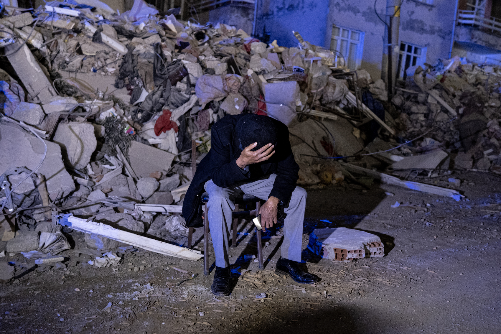 People waiting at the head of a building destroyed in the Turkey Syria earthquake