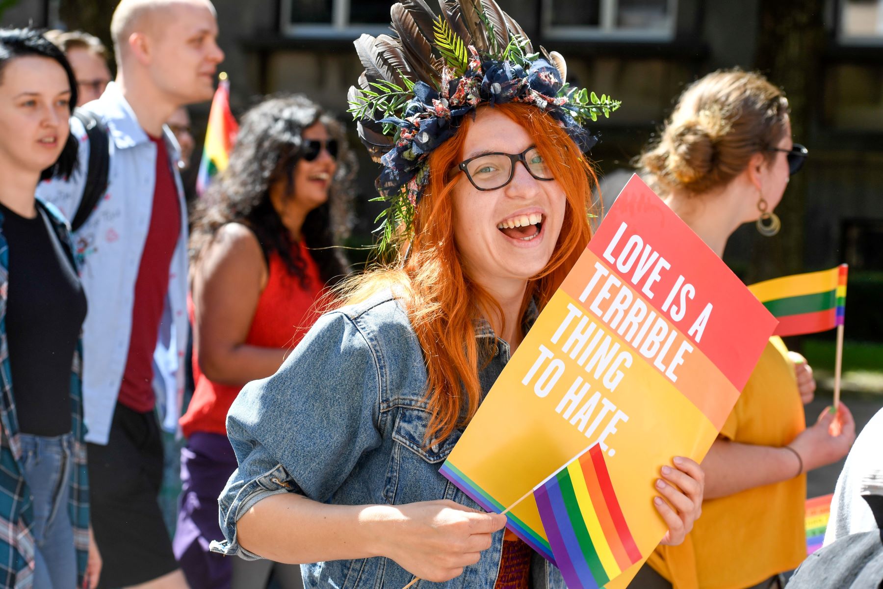 a woman holds a sign that says, "Love is a terrible thing to hate."