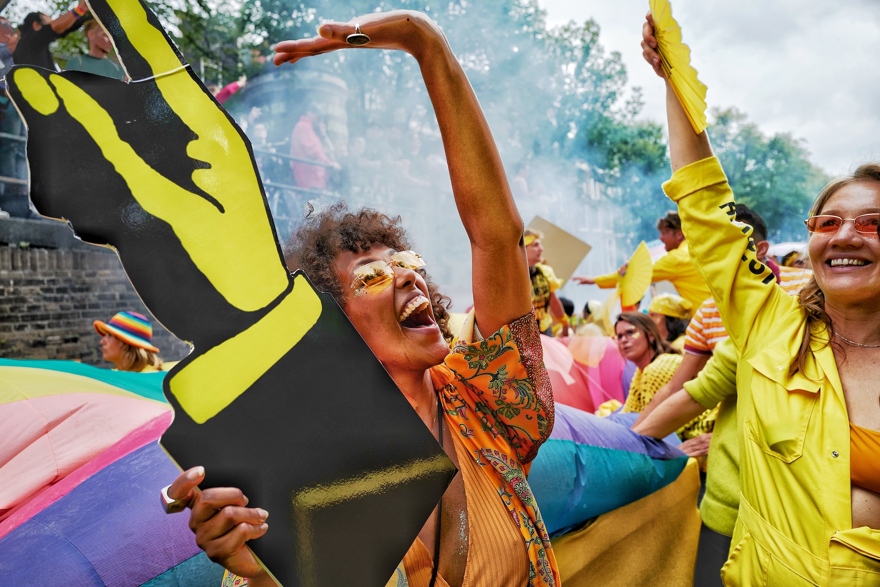 Woman holds a hand cutout and holds her hand out at Amsterdam Pride march.