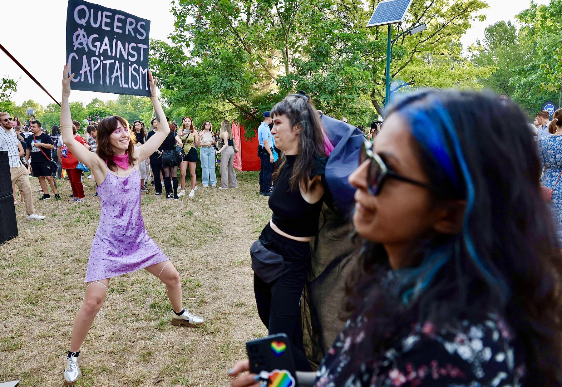 Woman holds sign that reads, "Queer against capitalism" at Romania's Pride march