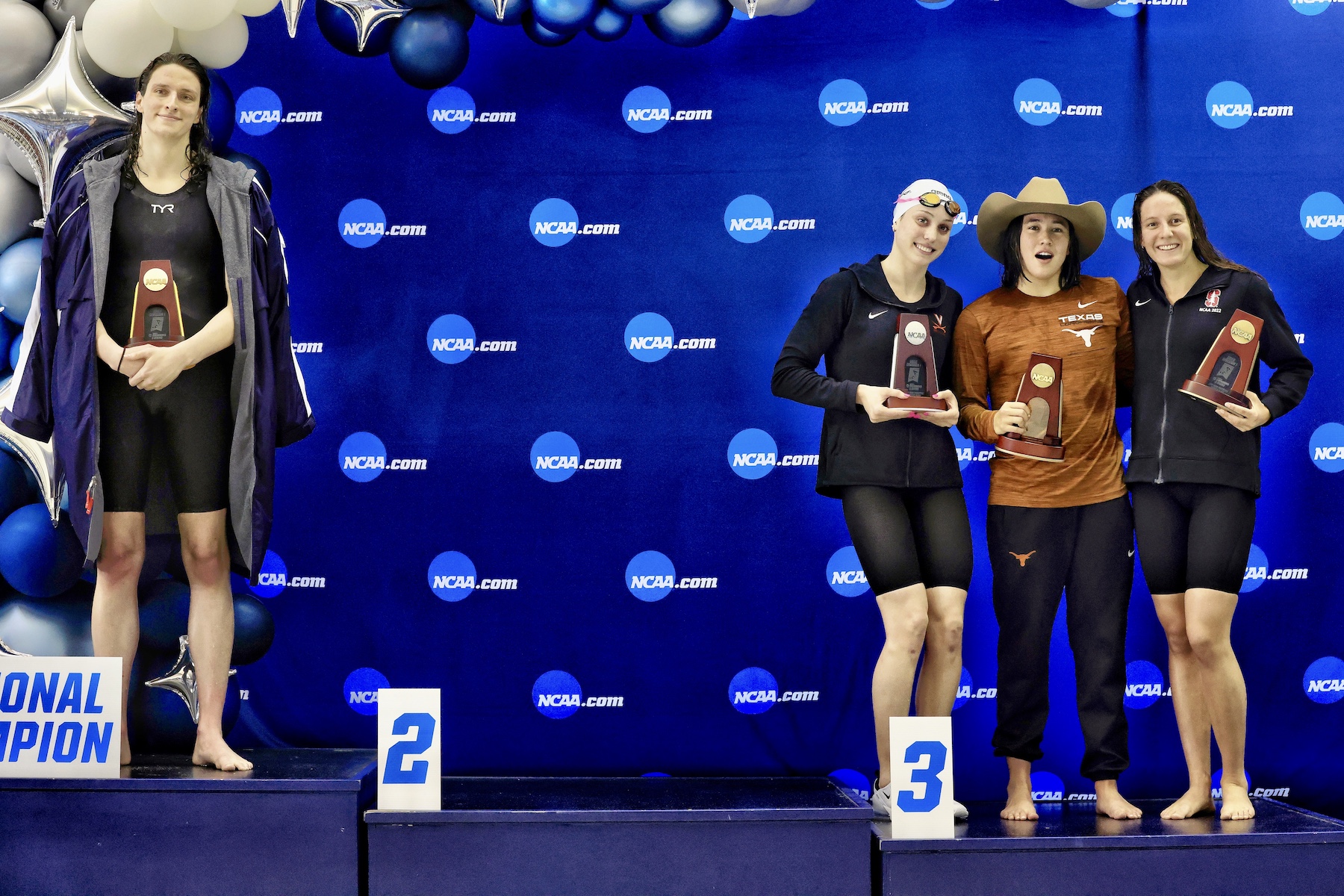 Transgender women Lia Thomas stands on the podium after winning as the other 3 medalists pose for a photo. 