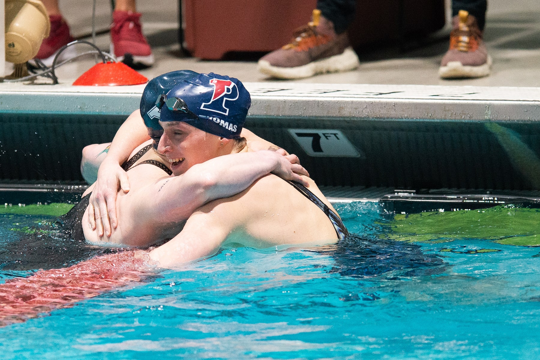 Trans woman swimmer Lia Thomas hugs trans man swimmer Iszac Henig.