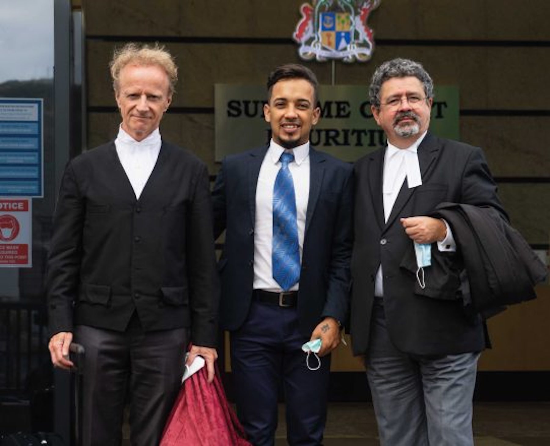 Gay activist, Ah Seek, stands in between two men at the front of Mauritius Supreme Court building