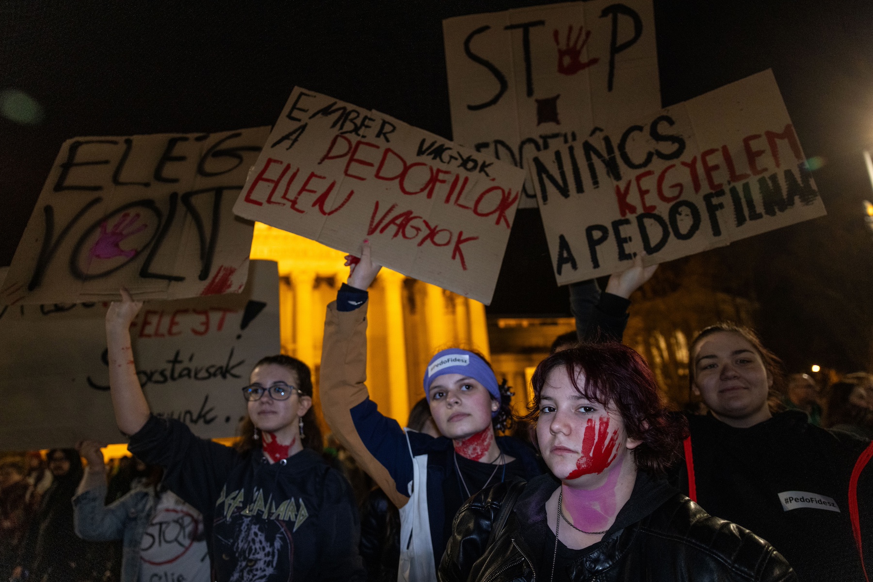 protesters holding banners hungary child sexual abuse viktor orban