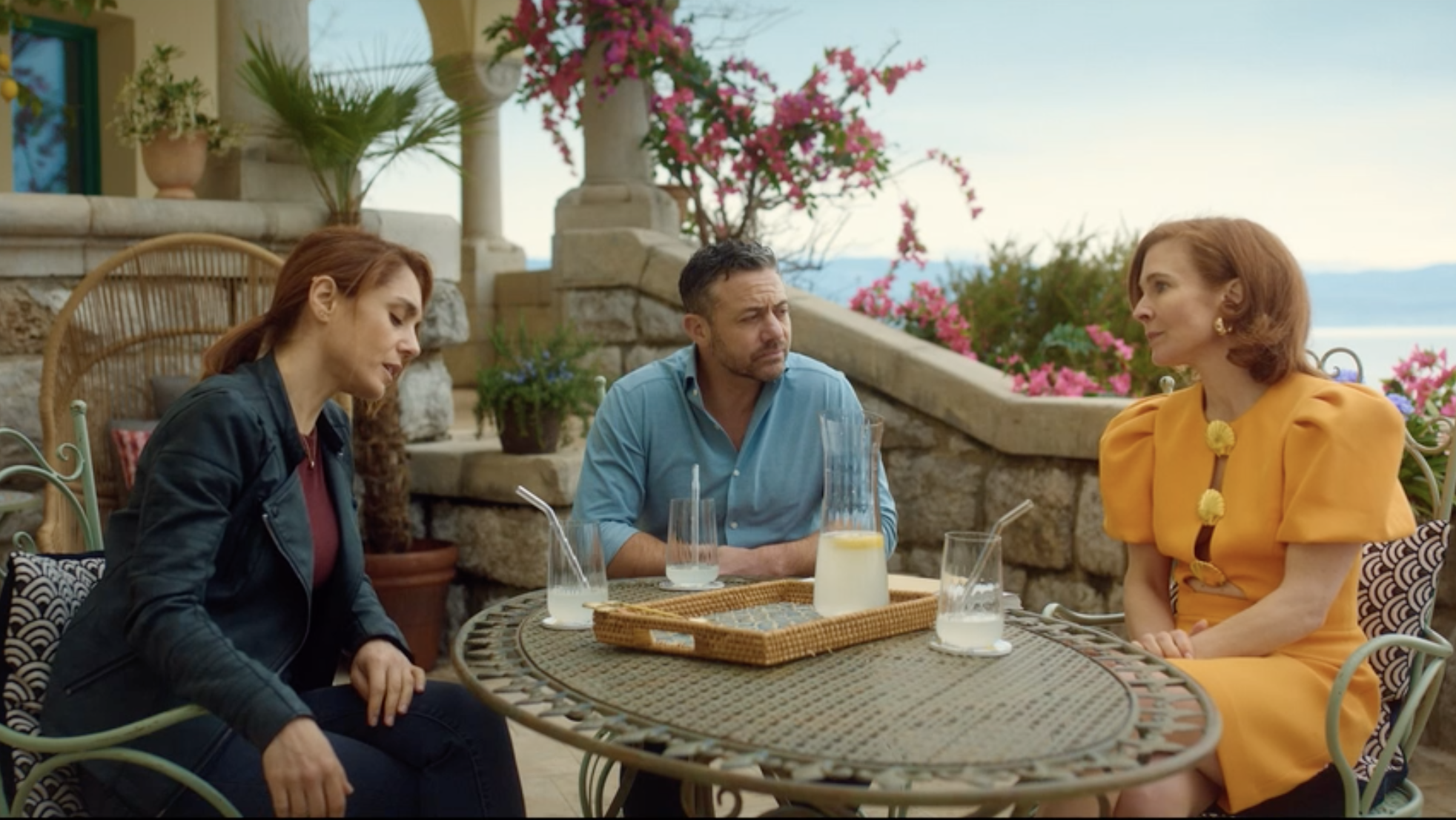 Lara (Cristiana Dell’Anna) and Joe (Warren Brown) interview Luisa Zenati-Hughes (Kaisa Hammarlund) seated outside her luxurious villa.