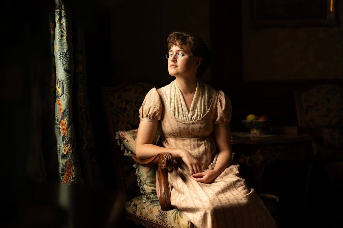 Mary Bennet (Ella Bruccoleri) sits in a sliver of light from a window.