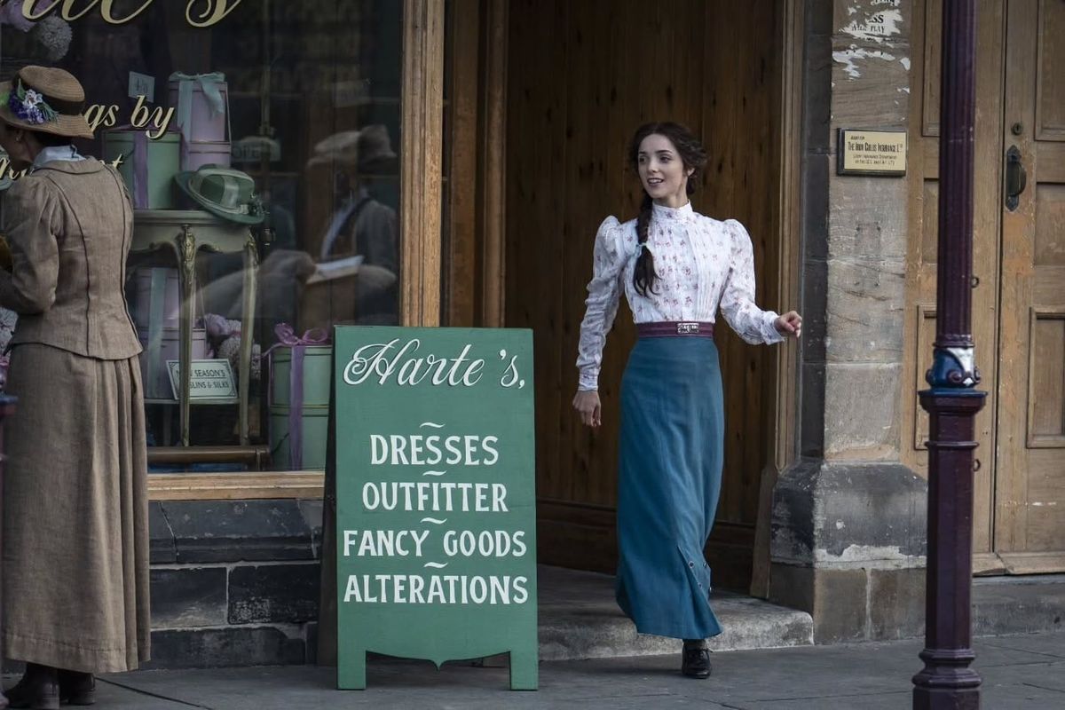 Emma Harte (Jessica Reynolds) steps outside her new shop.