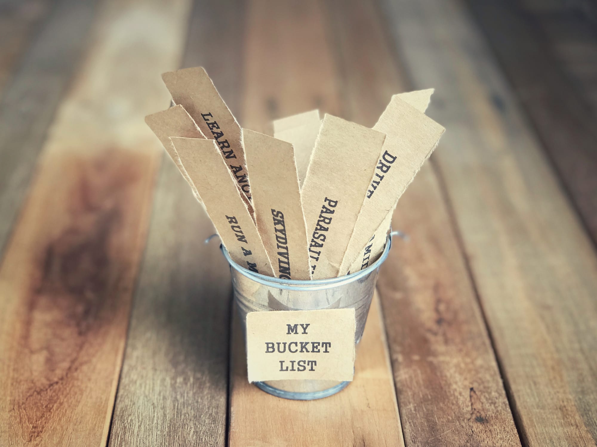 A bucket overflowing with small pieces of paper, each scribbled with a goal or dream set for "someday."