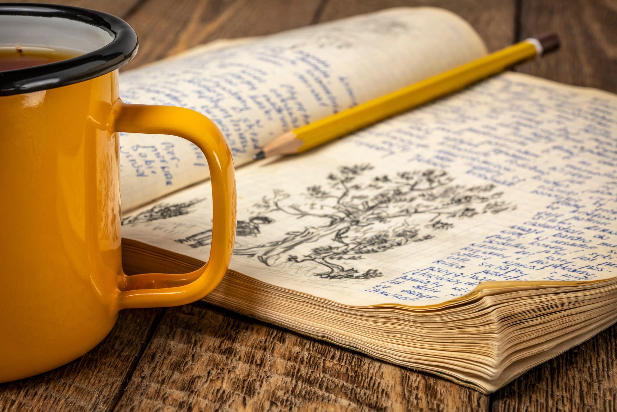 Open notebook with doodles and a coffee cup on a wooden table, symbolizing early struggles with journaling consistency.