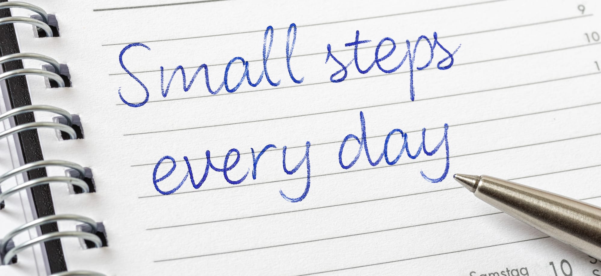 Overhead shot of an open journal with a simple, step-by-step plan written next to a pen.