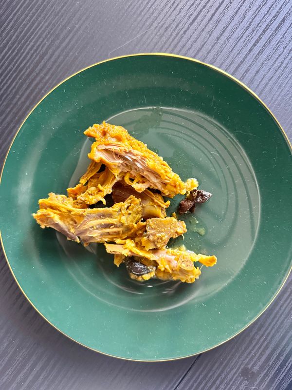 A green plate on a table, holding several chicken bones