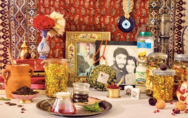 A collection of preserved vegetables, dried flowers, and nuts on a countertop alongside framed family photos
