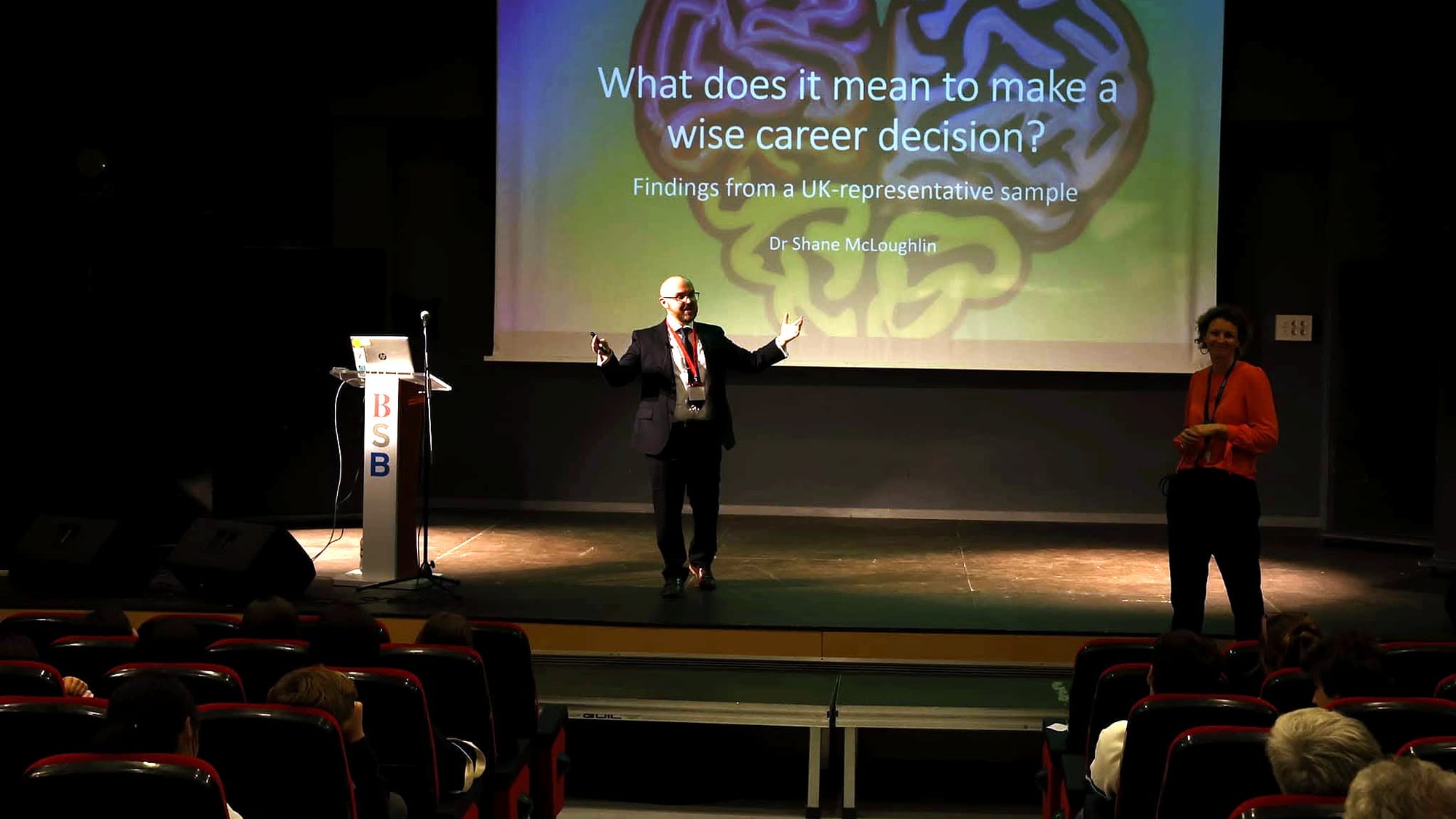 Shane McLoughlin speaking on stage to an audience