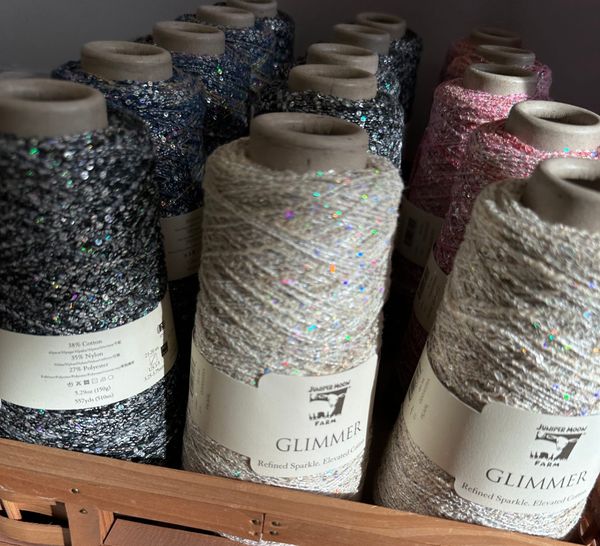 Rows of very sparkly spools of yarn/thread in the sun.