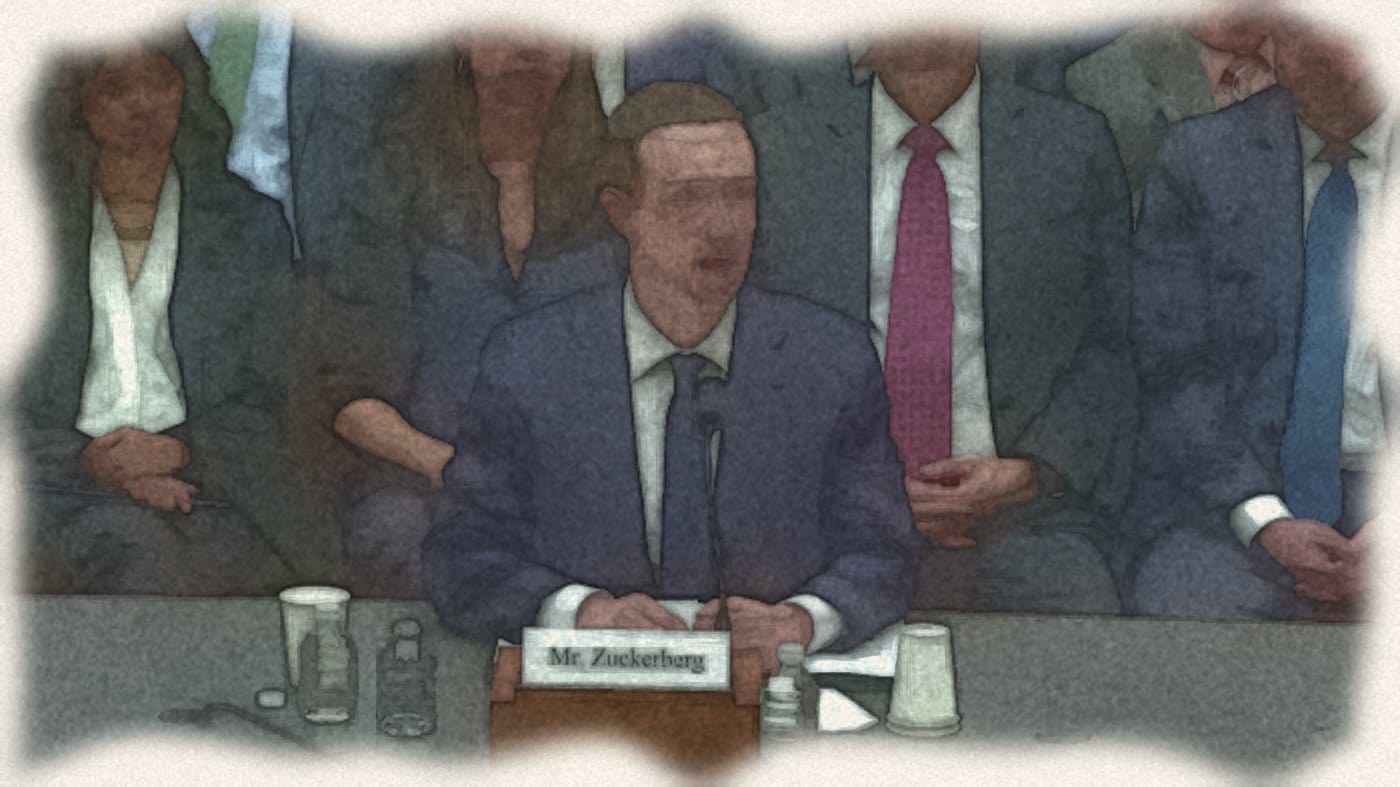 祖克柏坐在證人席麥克風前作證，身後坐著幕僚，桌上名牌寫著 Mr. Zuckerberg