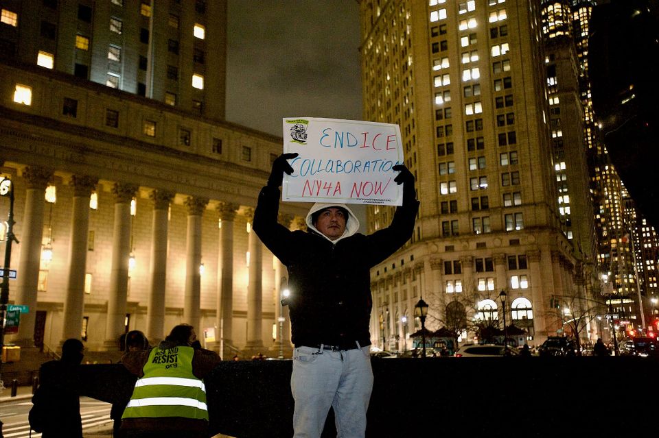 A man holding a sign to protest collaboration the Immigration and Customs Enforcement (ICE) agency.