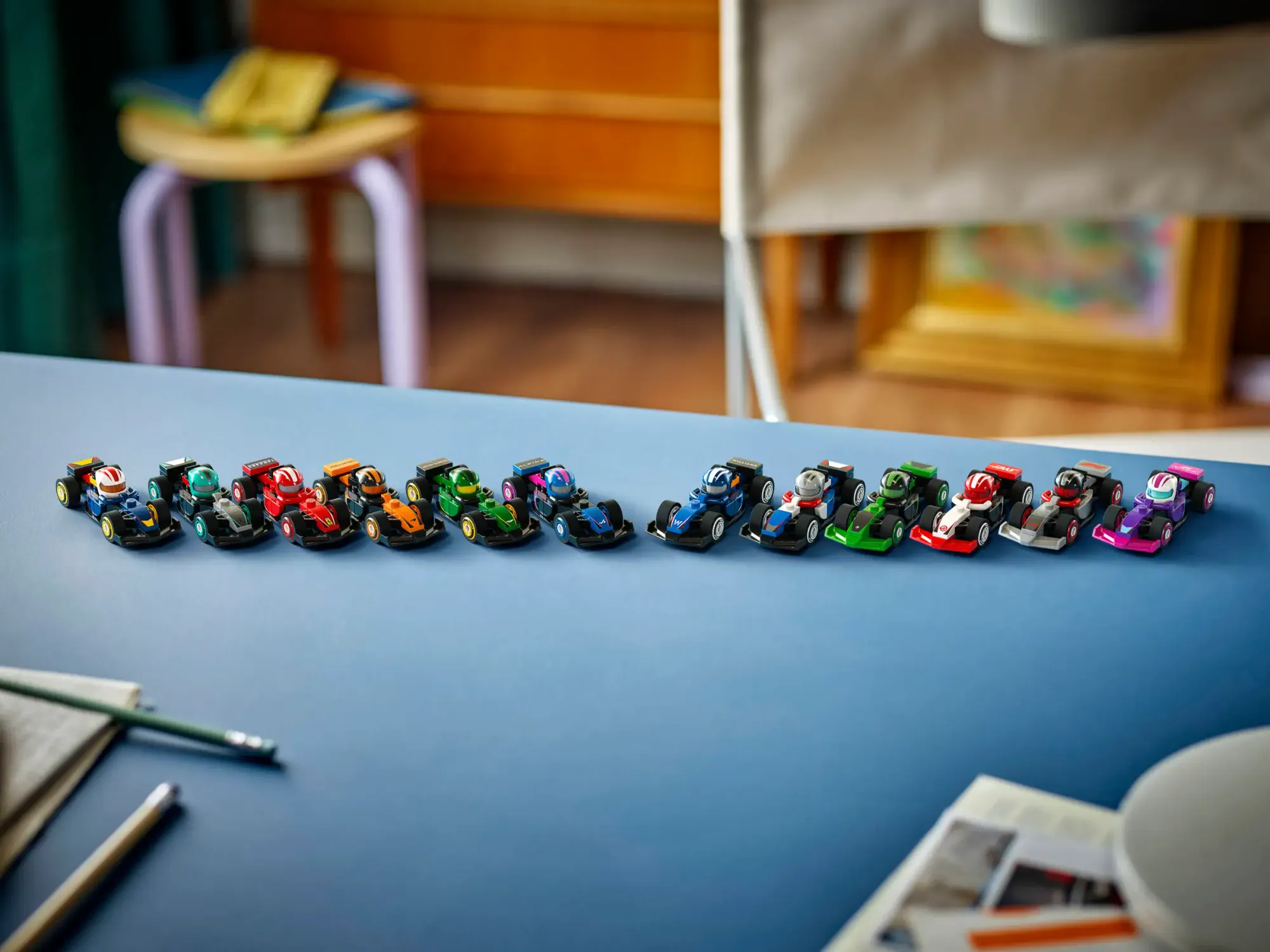 A shot of 12 very small Lego F1 cars on a blue desk.