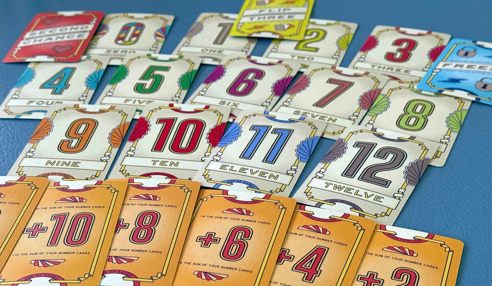 All cards are placed on a blue table. Zero through 12, six modifier cards, and three special cards.