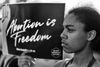Black and white photo of young Black woman holding up a sign that reads "Abortion is Freedom."