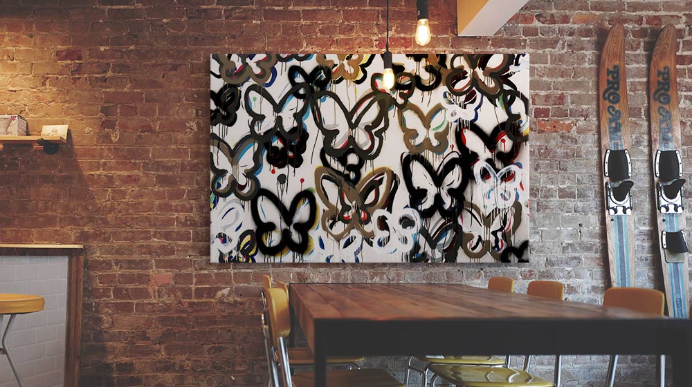 Spray paint graffiti butterflies on a canvas print in a brick wall dining room interior