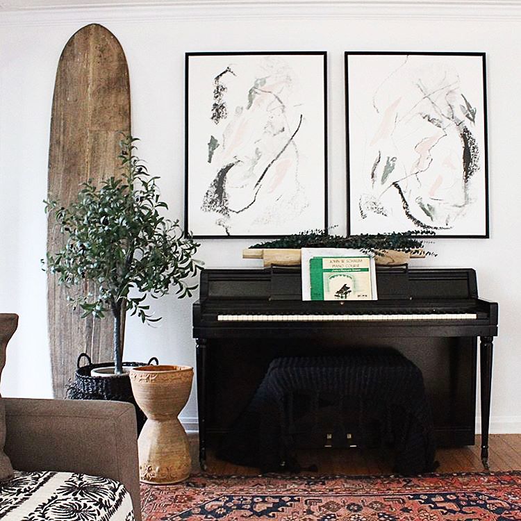 Pair of two abstract line art canvases with black frame over a piano in eclectic living room