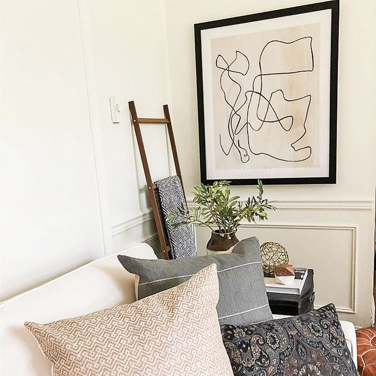 Bold line art print in black frame in a cozy living room.