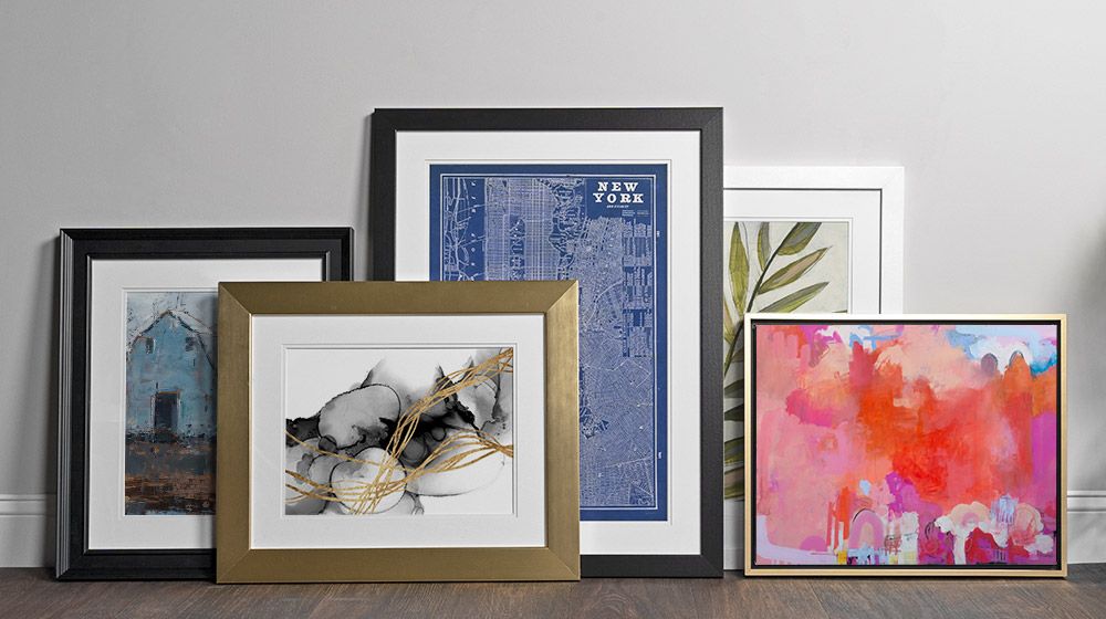 An assortment of framed art products leaning against a wall.