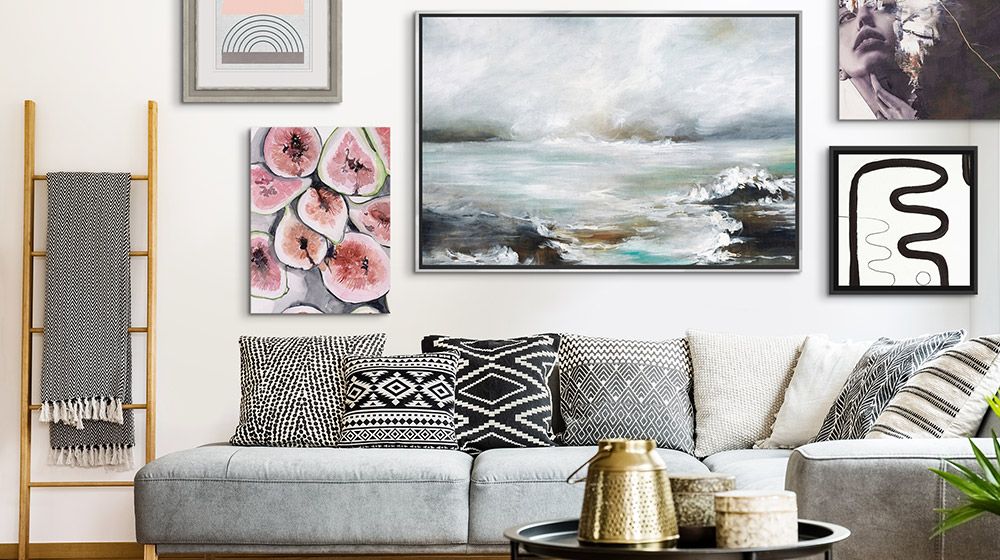 A wall display of a variety of canvas prints and framed art in a living room.