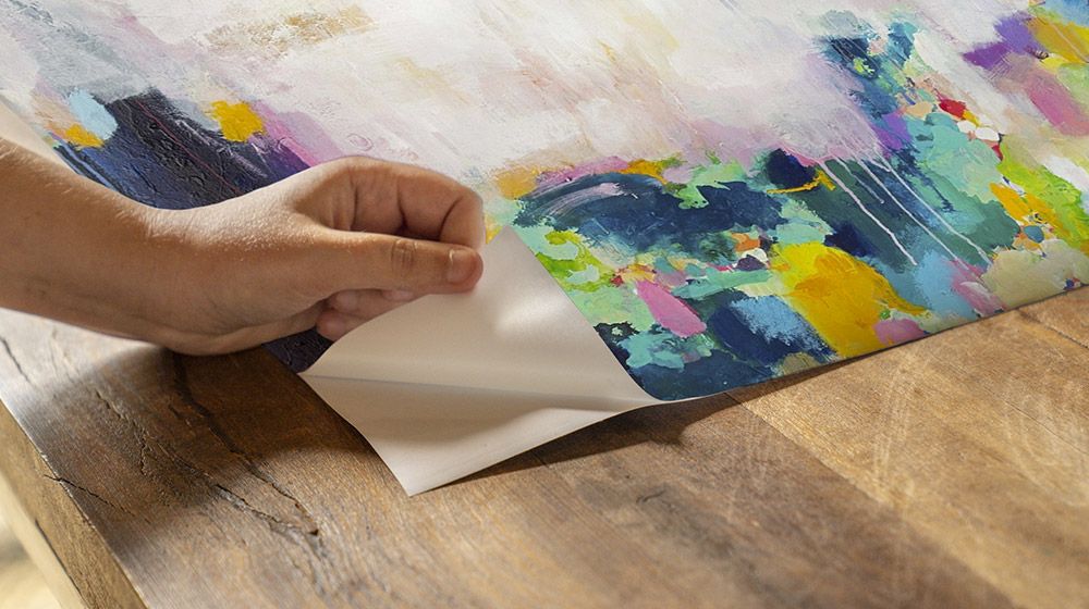 A woman preparing to hang an abstract art wall peel.