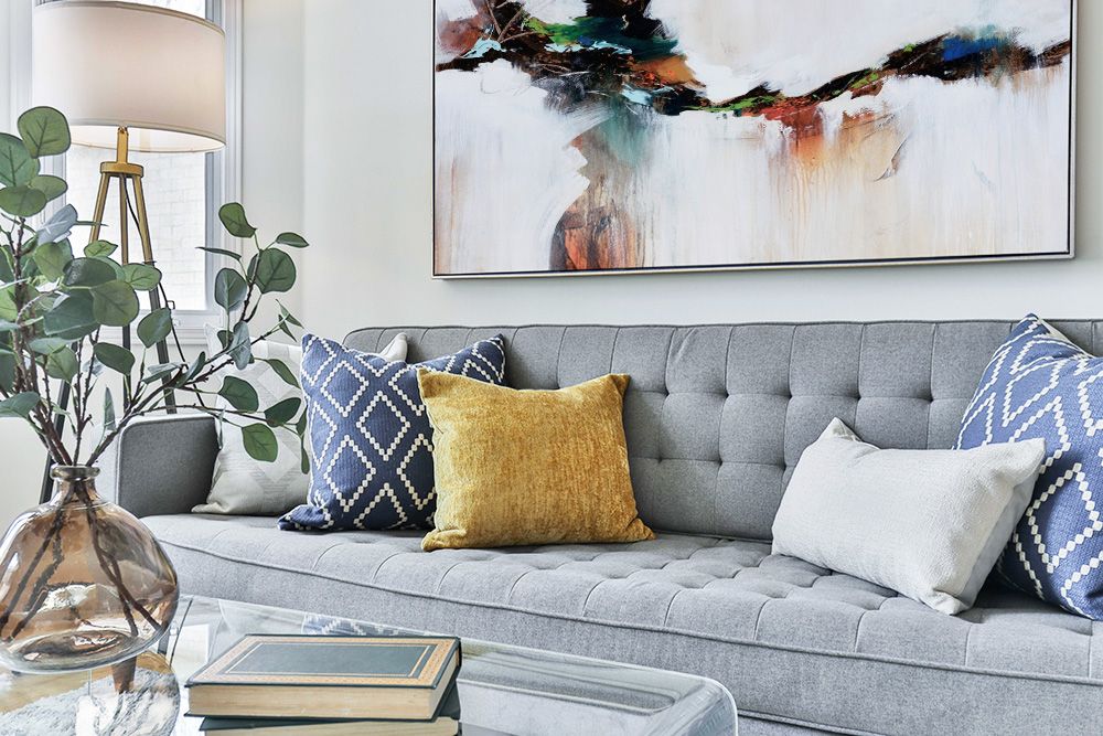 A luxury contemporary abstract in a silver float frame over a sophisticated living room couch.