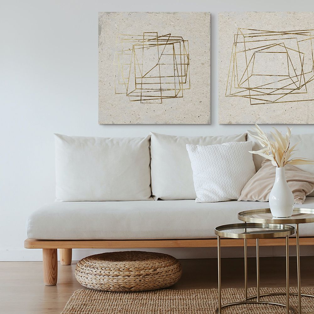 Two geometric giclée-style canvases with gold detailing over a white couch.