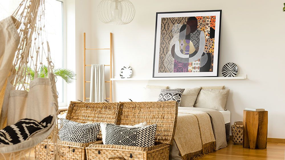 Family Ties Wall Art by Nikki Chu resting on a floating shelf above a bed draped with weaved, textured bedding