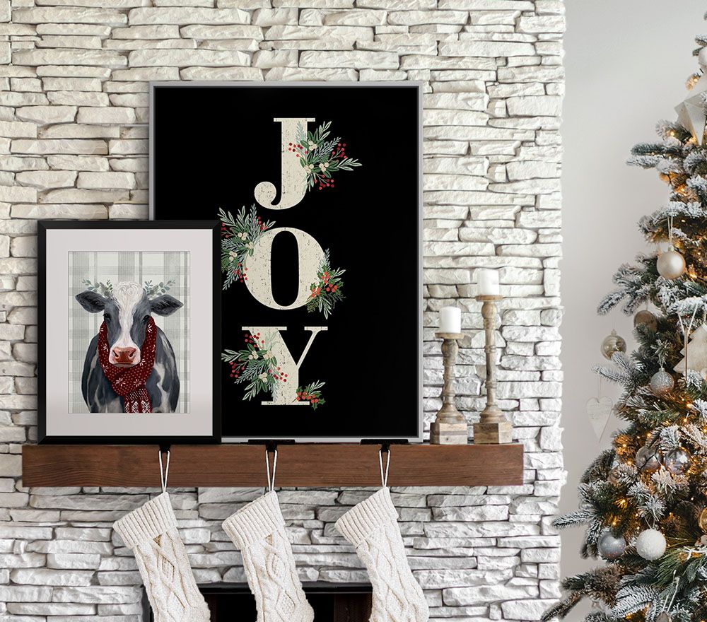 Yuletide Cow II by Victoria Borges, and JOY by Lori Siebert resting on a Christmas mantel