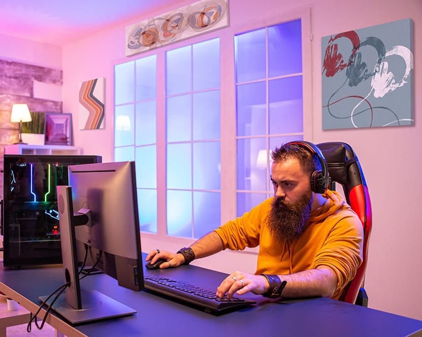 A man playing a PC video game in a room with minimalistic wall art