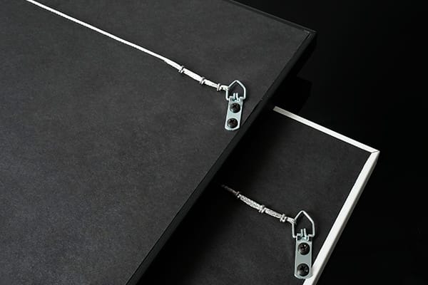 The back of two framed prints picturing D-ring and wire hanging hardware