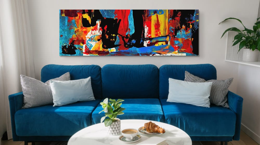 large colorful abstract canvas print over a big blue couch in a living room