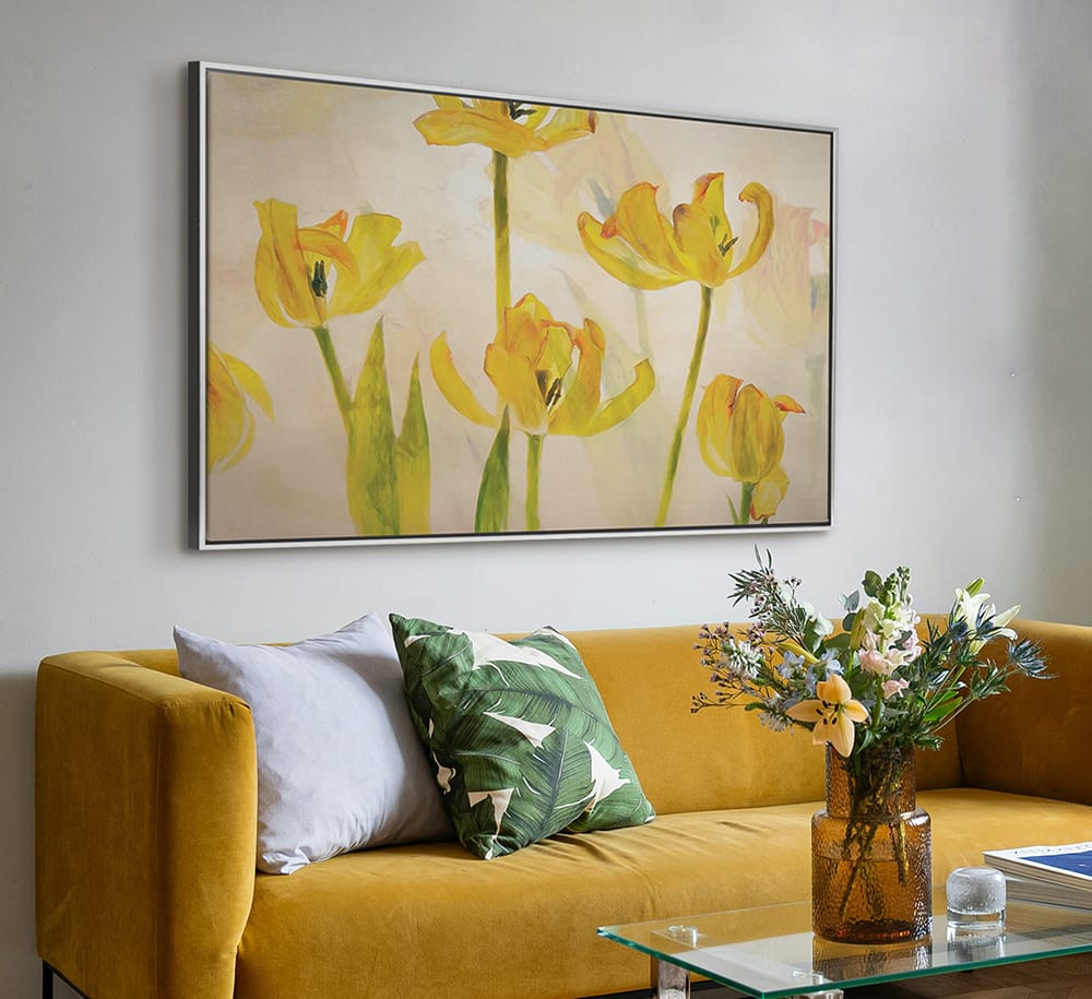 Bright yellow botanical wall art used as a focal point above a sofa with complementary decor