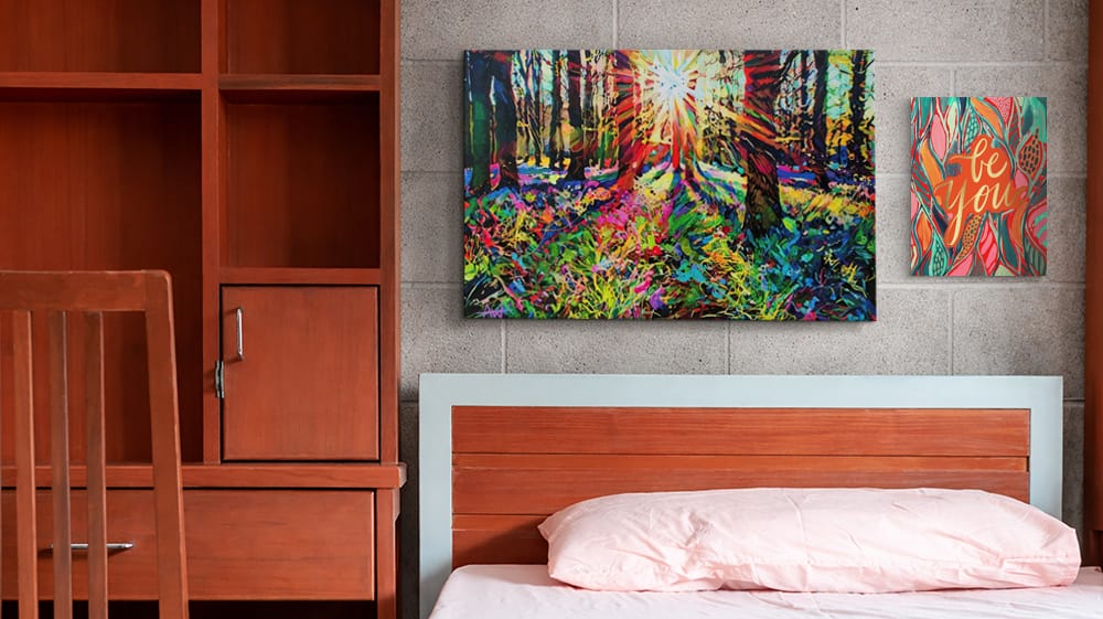 Dorm bed styled with colorful canvas wall art, demonstrating how bold prints add personality and define a small space