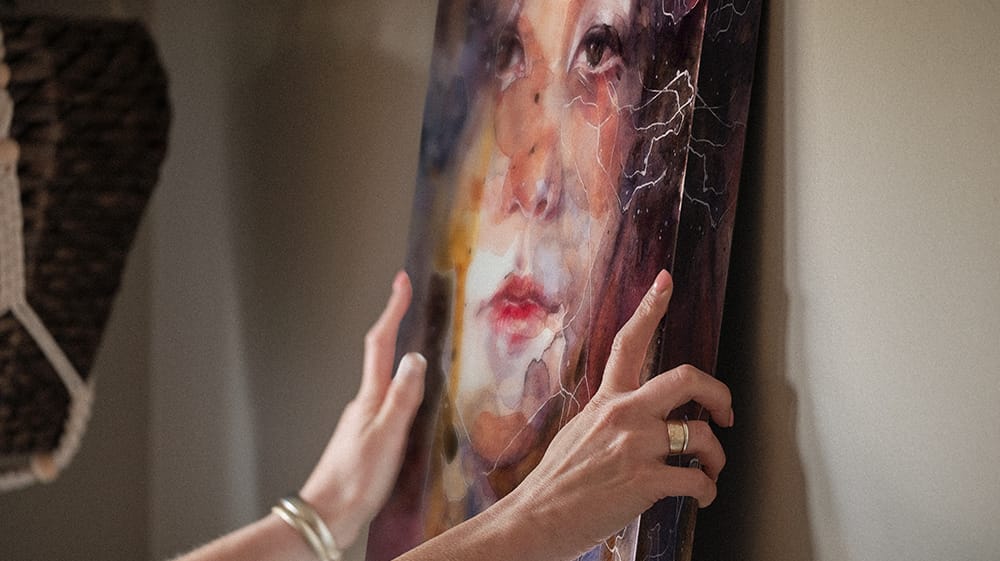 Hands positioning canvas wall art on wall, illustrating ease of hanging and finished look of stretched canvas