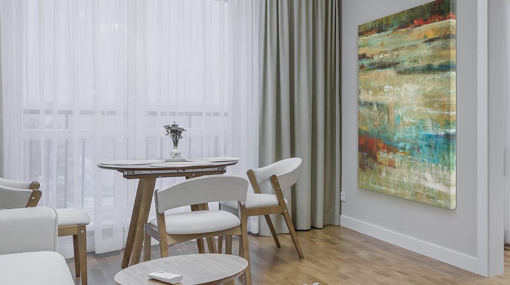 Oversized abstract wall art adding visual impact to a compact dining space with modern furniture