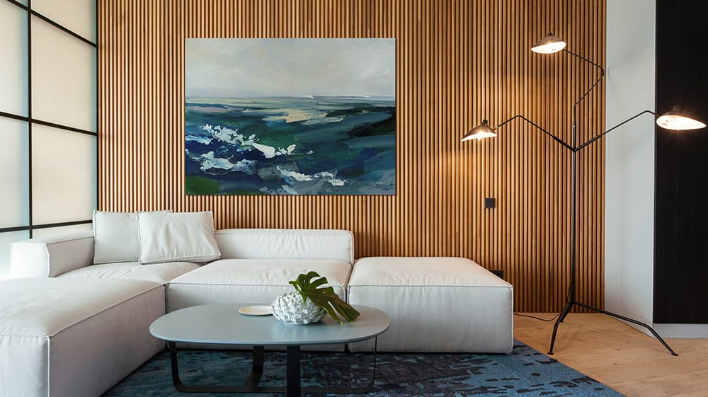 Painterly wall art depicting an abstract oceanscape hanging on a textured wall in a modern living room