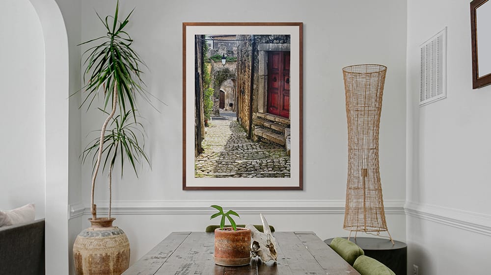 Framed travel photography of a European cobblestone street, illustrating how personal travel art adds character and storytelling to a space