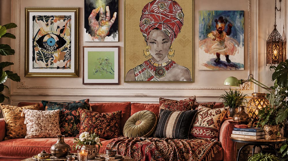 Warm global maximalist living room combining patterned textiles, figurative wall art, metallic accents and an eclectic mix of decor.