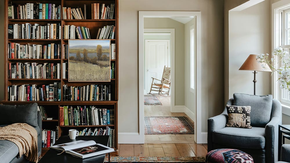 Two colorful canvas prints hang from the outer face of a bookcase in a home office, adding artwork without taking up additional wall space.