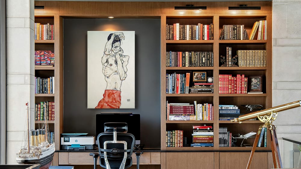 Expressive figurative artwork hangs between built-in bookshelves in a home office, showing an elongated figure against a light background.